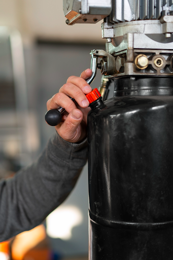 Close-up of a technician adjusting a control valve on an industrial rotary screw air compressor during maintenance